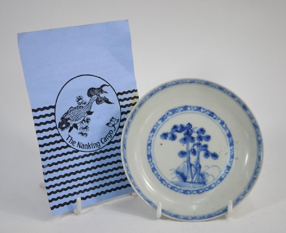 A Nanking Cargo blue and white saucer dish with: A small Chinese Export blue and white saucer dish, decorated with a central pine tree; the base with Christie's/ The Nanking Cargo label/ Lot 5537 (2) Provenance: sold with a Regent Fine Art at Libert