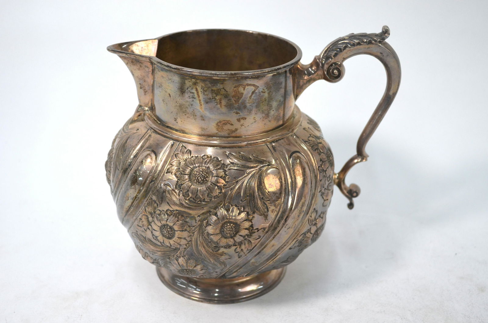 Late Victorian silver jug: A late Victorian silver globular jug with scroll handle and floral embossed and chased writhen decoration, Charles Stuart Harris, London 1898, 18 oz, 14.5 cm high