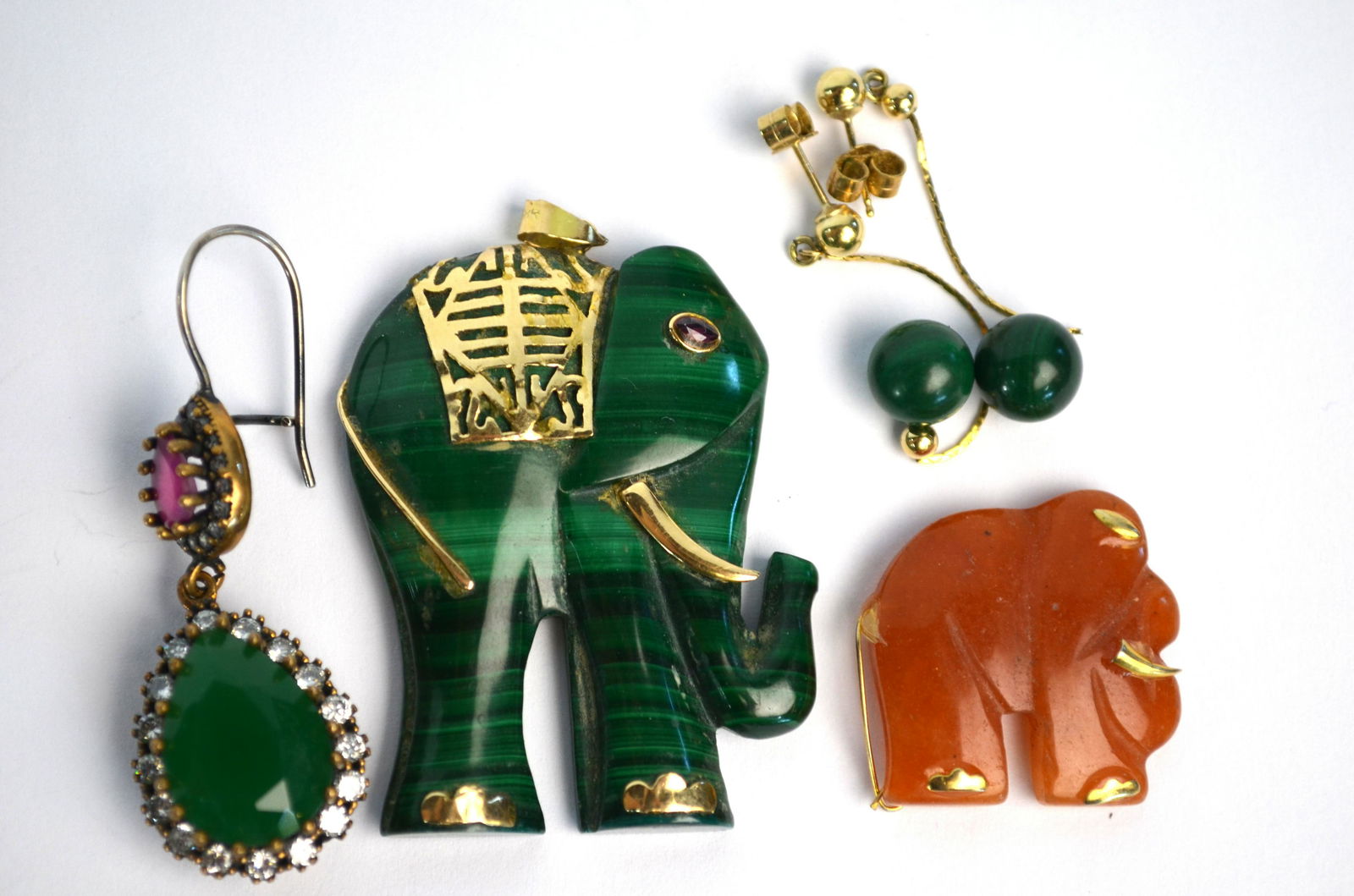 A malachite pendant carved as an elephant: A malachite pendant carved as an elephant with yellow metal mounts of toes, tusk, tail and saddle, with hanger stamped 14k and ruby set eye, 4.5 x 3 cm to/w chalcedony elephant, pair of malachite earr