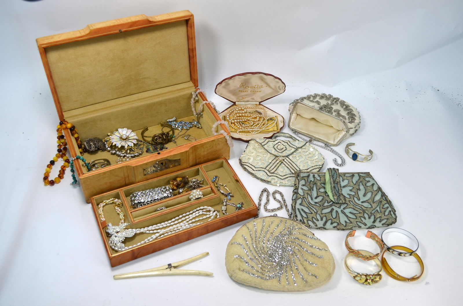 A tan leather jewel case containing a quantity of: A tan leather jewel case containing a quantity of costume jewellery including paste set expanding cuff, simulated pearl necklaces, amber bead necklace, bangles, paste-set necklaces, brooches, earrings
