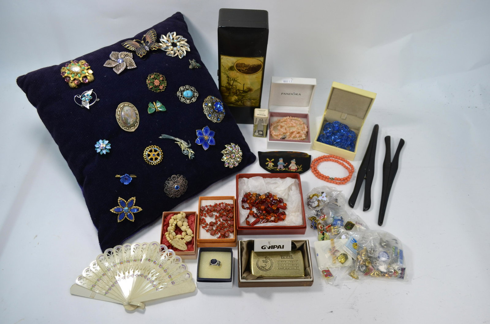 A collection of costume jewellery brooches and other: A collection of costume jewellery brooches, some enamel, some paste set, pinned to a cushion to/w various bead necklaces, quantity of collectors lapel badges, glove stretchers in vintage box, cigar cu