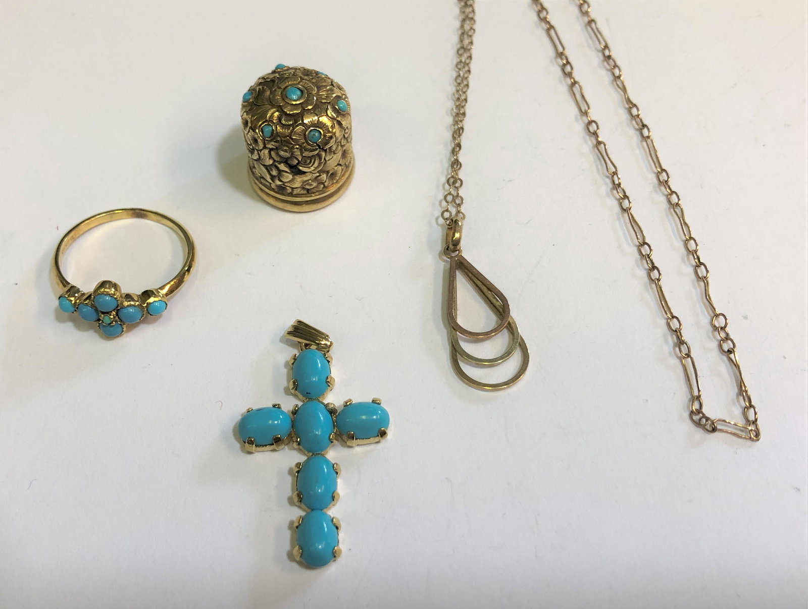 A 9ct yellow gold ring set with turquoise beads: A 9ct yellow gold ring set with turquoise beads in the form of a cross, size M; a 9ct yellow gold pendant cross set oval turquoise; a gilt metal ornately chased bottle top/thimble set turquoise; an 18