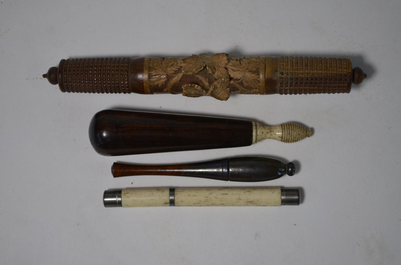 Three carved and turned wood needle cases: Three carved and turned wood needle cases and a bone example with base metal mounts (4)