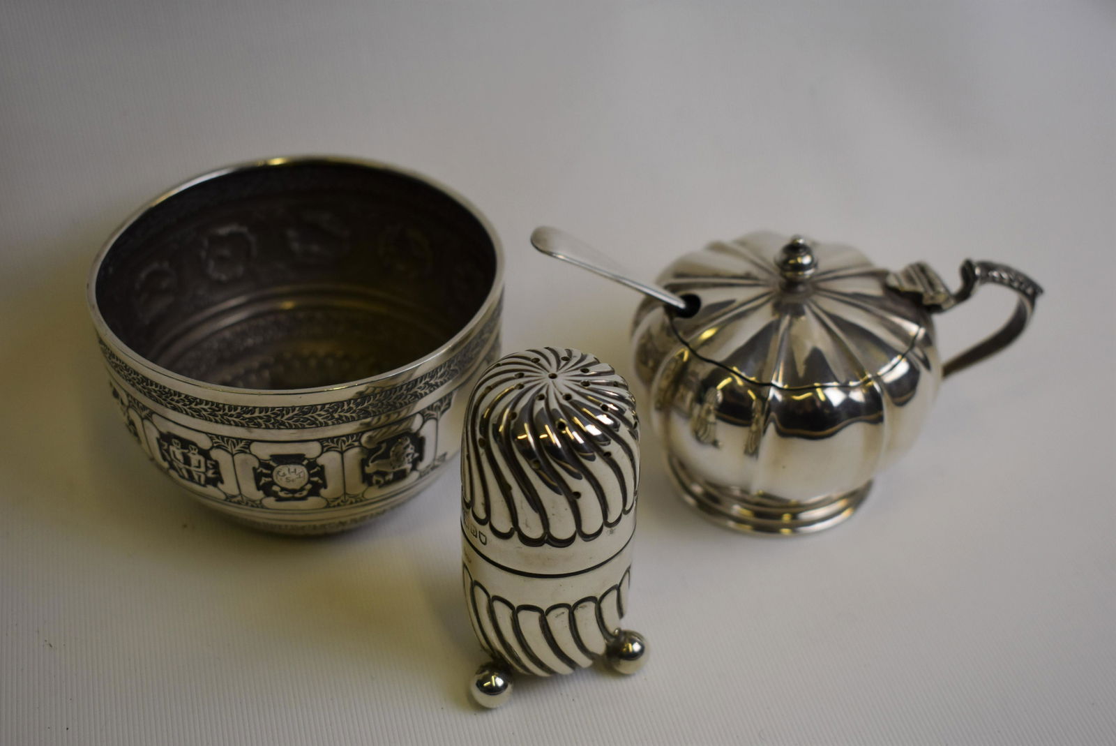 A Victorian chased silver sugar basin etc.: A Victorian chased silver sugar basin worked with the Signs of the Zodiac, Charles Stuart Harris, London 1886, 8 cm diameter, to/w a spiral-reeded pepperette, London 1897 and a melon-shaped mustard, B