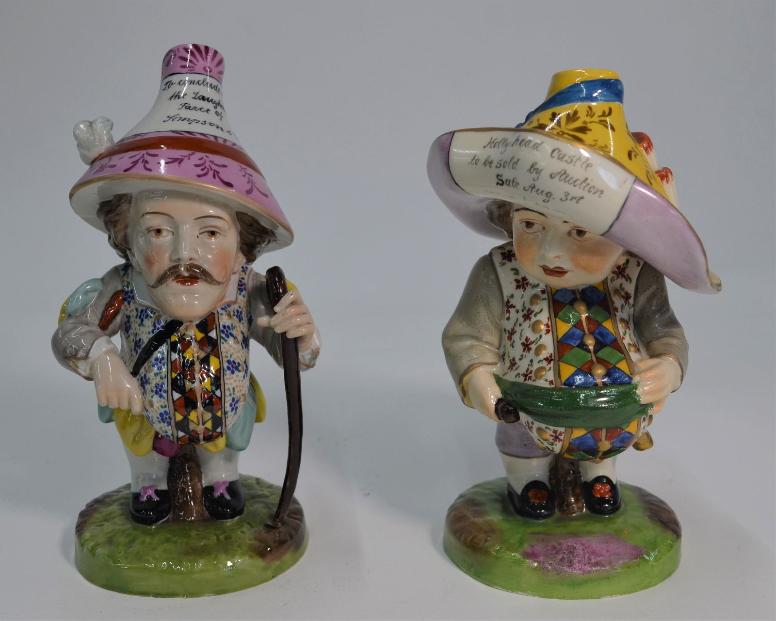 Two Mansion House dwarfs: A Derby model of a Mansion House dwarf, inscribed to hat 'Hollyhead Castle to be sold by Auction Sale Aug 3rt(sic), puce painted mark to base, 17 cm high to/w another porcelain Mansion House dwarf bea