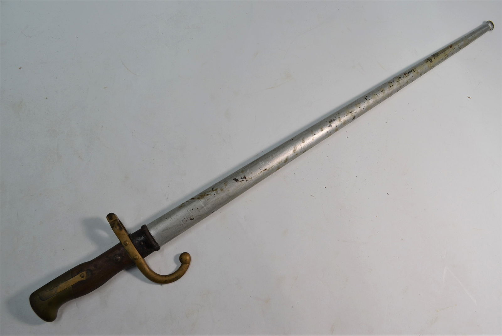 A 19th century French 1874 pattern bayonet: A 19th century French 1874 pattern bayonet, the 51.5 cm blade with flattened back-rib inscribed Mme d'Obemes de St. Etienne 1877, brass hilt with two-piece wooden grip, in steel scabbard