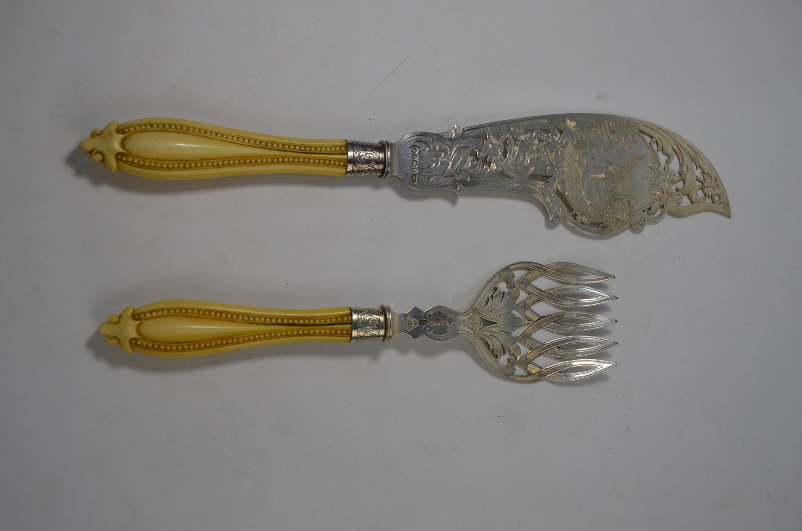 A Victorian pair of engraved and pierced silver fish: A Victorian pair of engraved and pierced silver fish servers with carved ivory handles, Joseph Rogers & Sons, Sheffield 1861