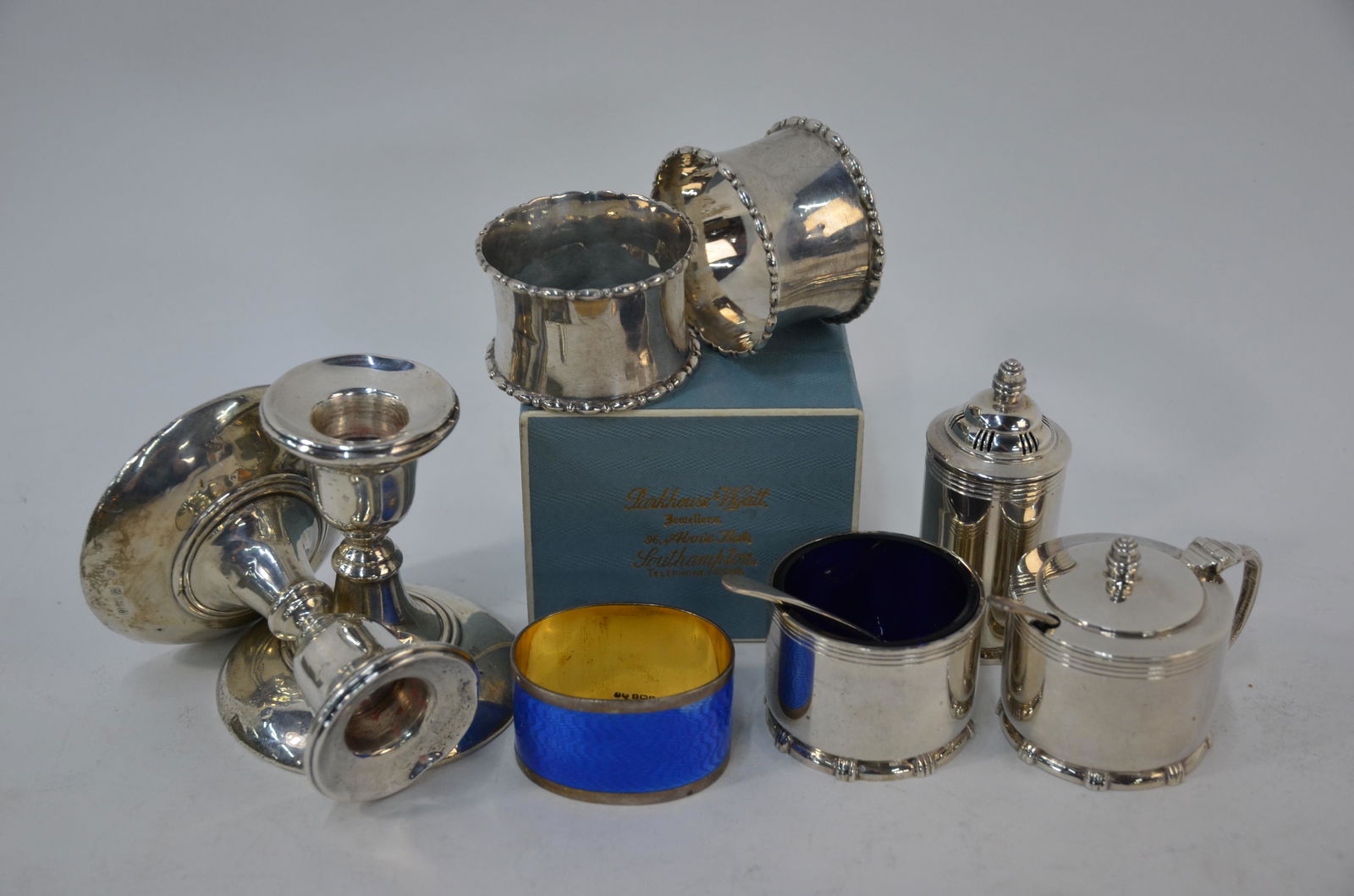 A box of silver items including napkin rings: A silver gilt and enamel napkin ring, Birmingham 1930 to/w a boxed pair of napkin rings, Birmingham 1911, five various other napkin rings, an Art Deco three piece condiment set, Birmingham 1939 and a