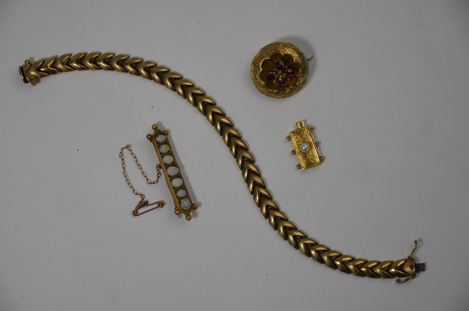 A Victorian target brooch set with garnet flower: A Victorian target brooch set with garnet flower, vacant locket at back, an early 20th century bar brooch set with seven pale opals, a yellow metal necklace clasp stamped 14k set with small pearl (pro