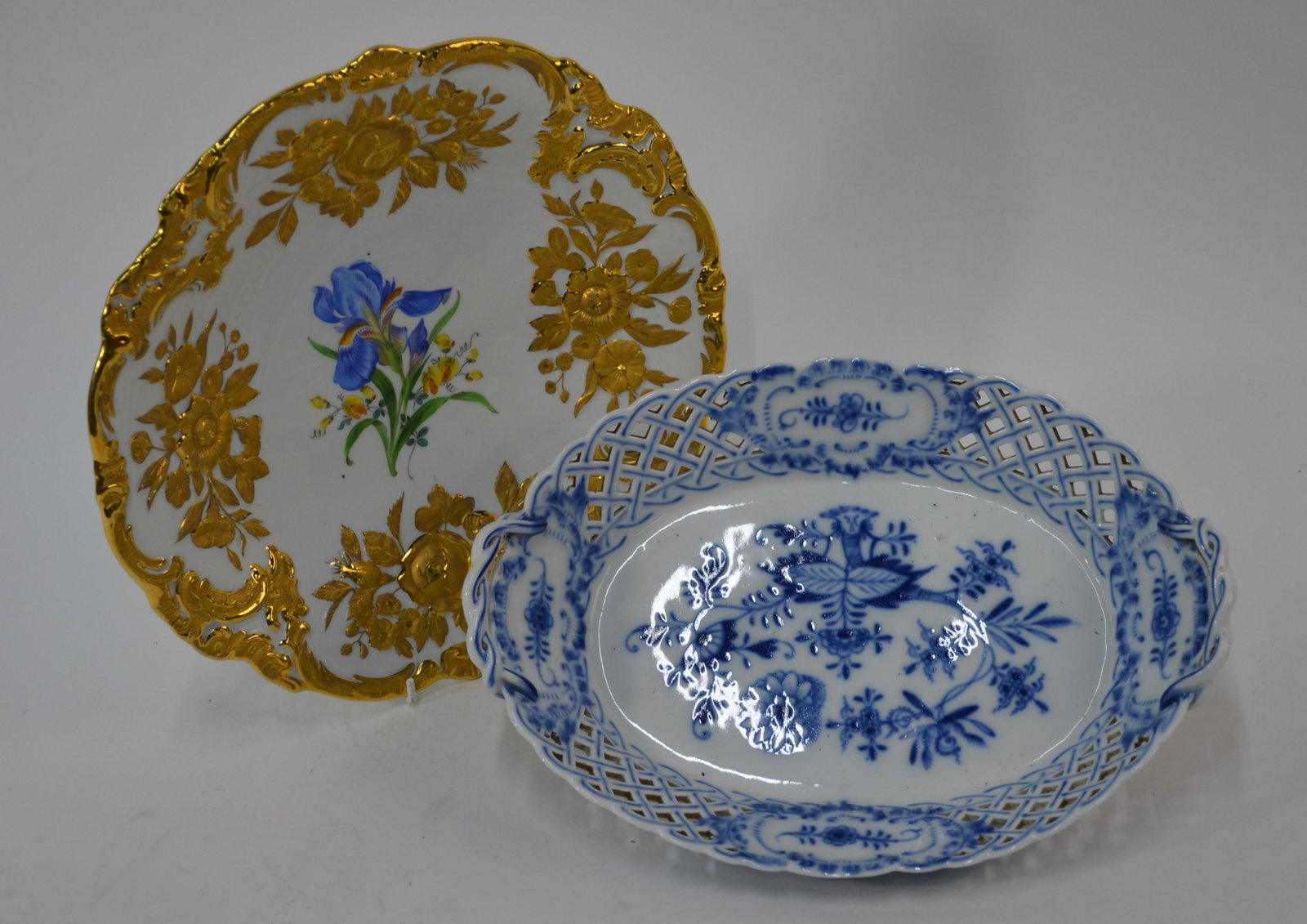 Two Meissen bowls: A Meissen floral moulded and gilded shallow bowl, painted to the centre with blue irises, underglaze blue crossed swords to base, 28 cm diam. to/w a Meissen ovalÂ reticulated twin handle fruit baske