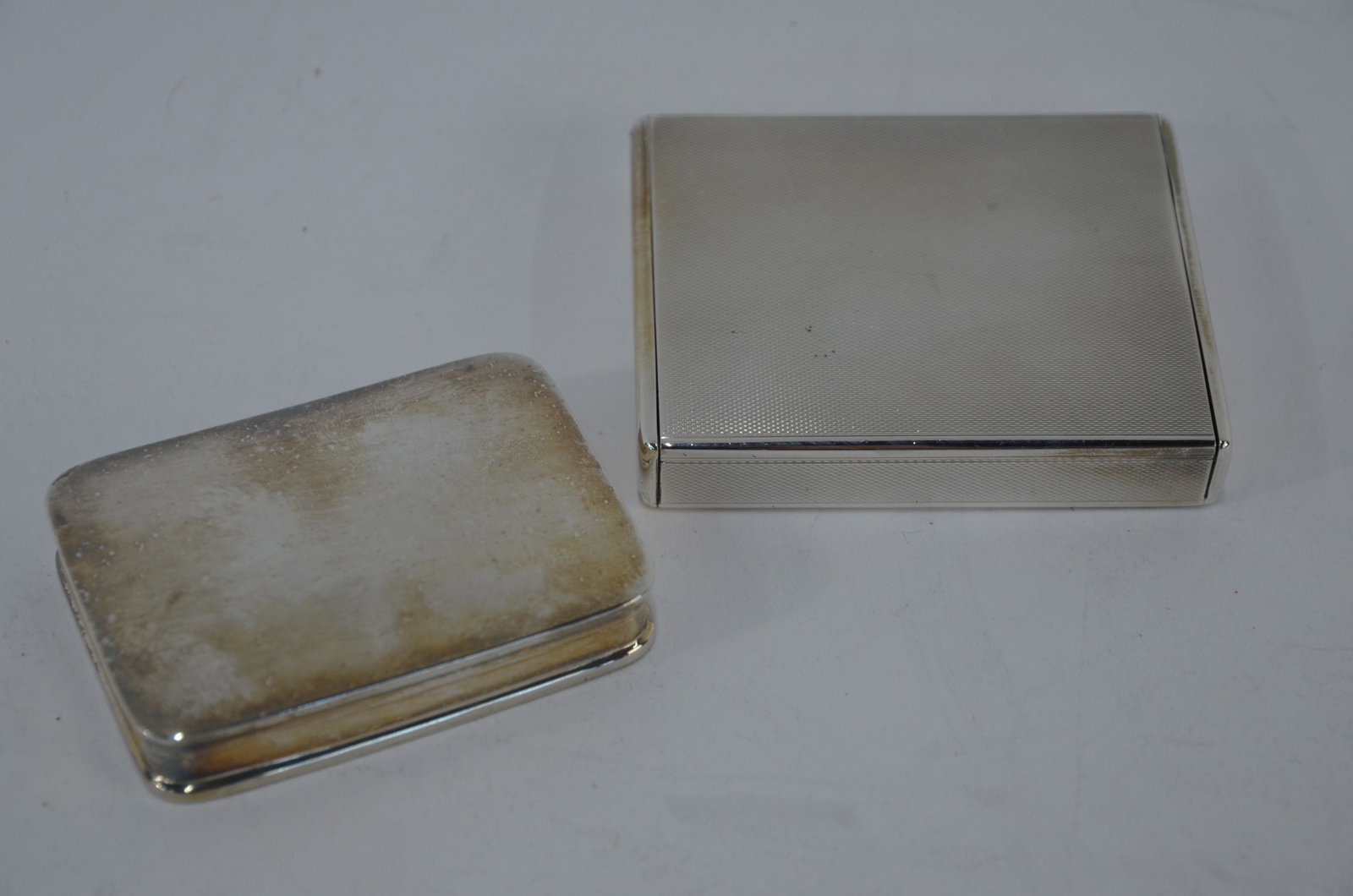 A Continental Sterling silver minaudiere and a pill box: A Continental Sterling heavy quality engine-turned minaudiere (cosmetic case), with gilt interior and sprung cover, 8 x 6.5 cm to/w a silver pill-box with hinged lid, London import 1995, 7 cm wide (2)