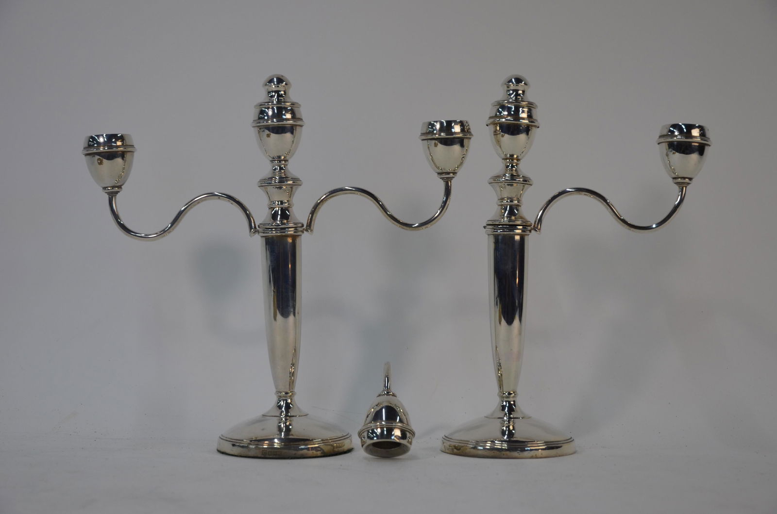 A pair of silver twin branch candelabra: A pair of loaded silver three-sconce candelabra with twin branches and drop-in central plugs, on baluster columns and circular bases, J B Chatterley & Co, Birmingham 1965 (unscrewing to convert to eit