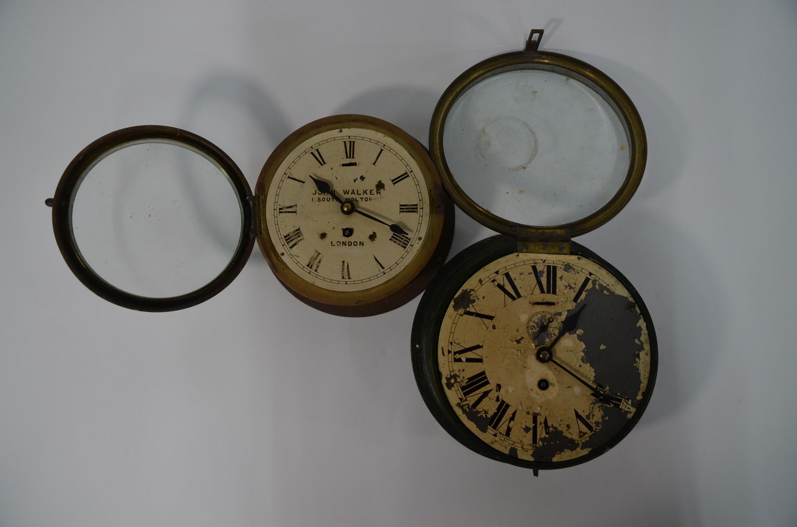 Two brass bulkhead clocks: John Walker,1 South Molton, London, an old brass bulkhead clock, the verso stamped 10048, a/f, 20 cm dia, to/w another larger bulkhead clock, 23 cm diam (2)