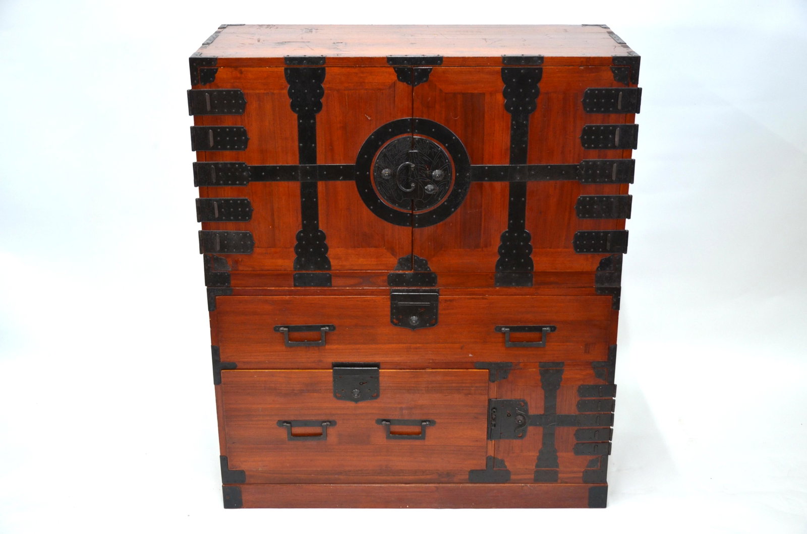 An early 20th century Japanese bridal chest, Yomeiri: An early 20th century Japanese bridal chest in two sections standing on a plinth base, Yomeiri Dansu, Meiji or Taisho period, stained camphor wood with iron mounts, locks, handles and fittings, the to