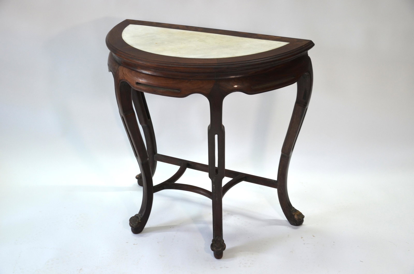 A late 19th or early 20th century Chinese hardwood: A late 19th or early 20th century Chinese hardwood console table, the moulded demi-lune top with inset white marble panel and shaped frieze raised on curved supports united by stretchers and 'shou' sy