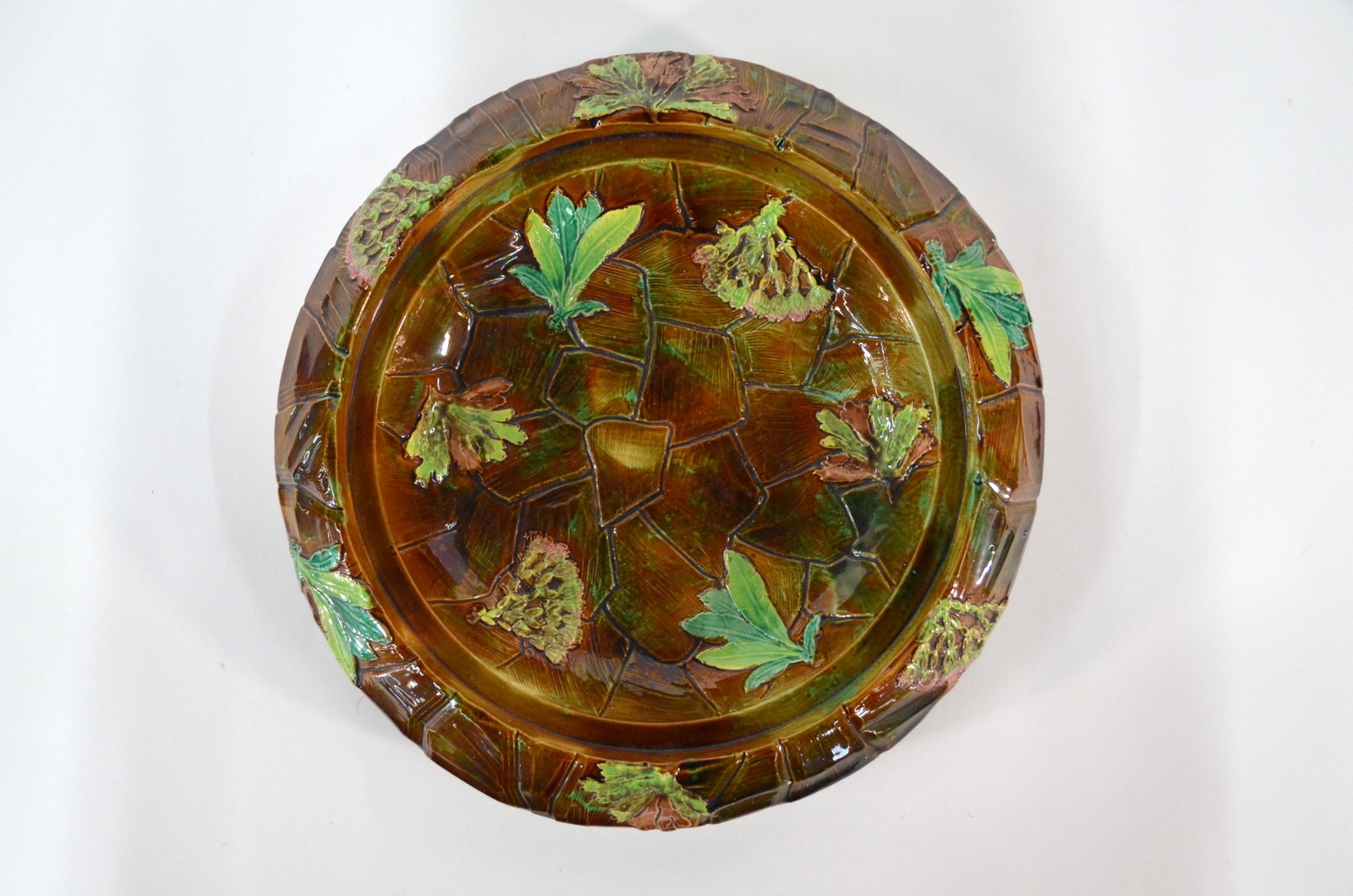 A Victorian George Jones & Sons majolica cheese dish: A Victorian George Jones & Sons majolica cheese dish, embossed with foliage on 'crazy paving' ground, in green and brown colour-way, 30 cm diam