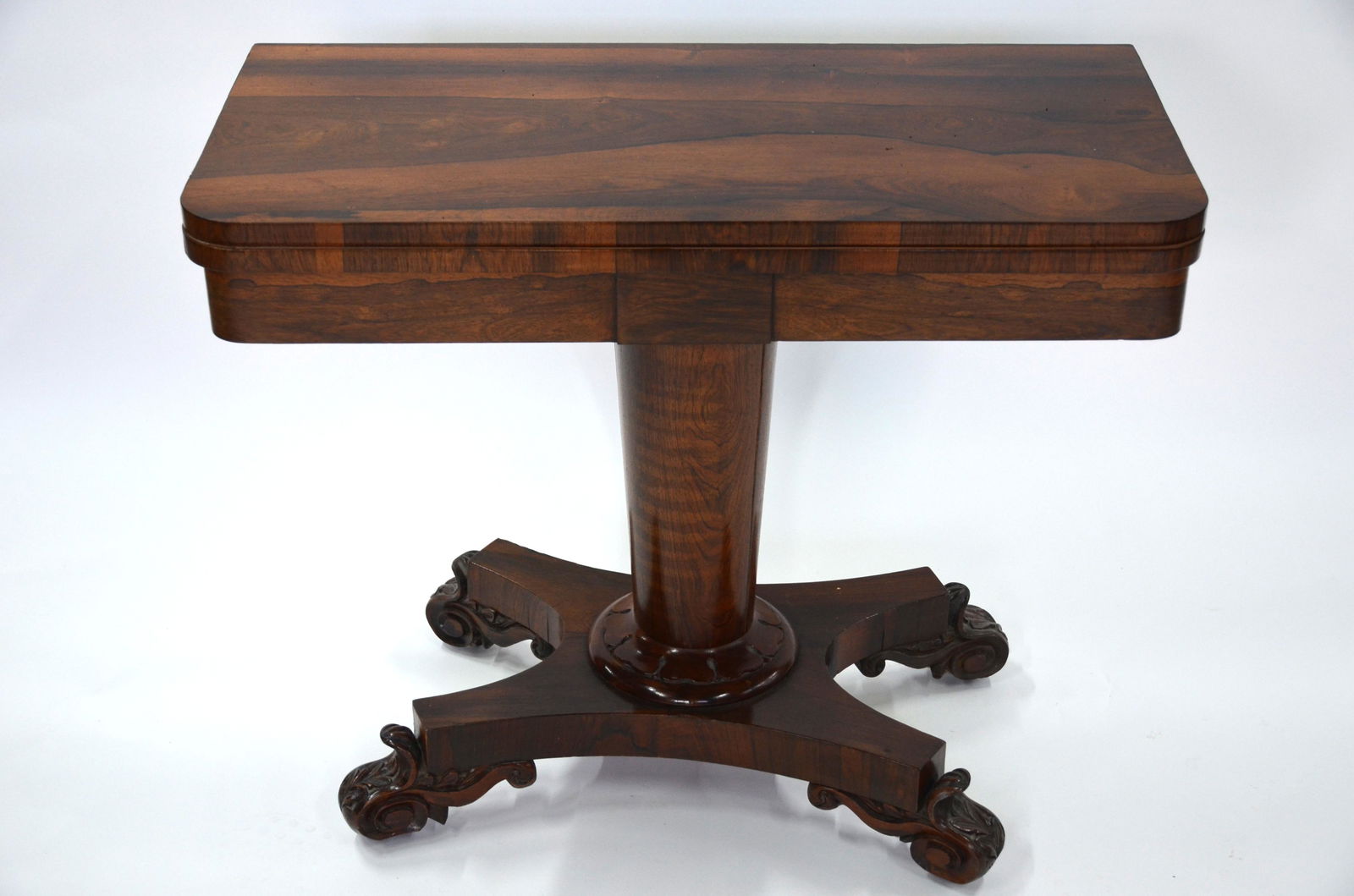 A 19th century rosewood fold-over card table: A 19th century rosewood fold-over card table, with circular baize lining raised on a turned support to a quad platform base, on moulded feet and concealed castors, 91.5 cm w x 45 cm (closed) x 74.5 cm