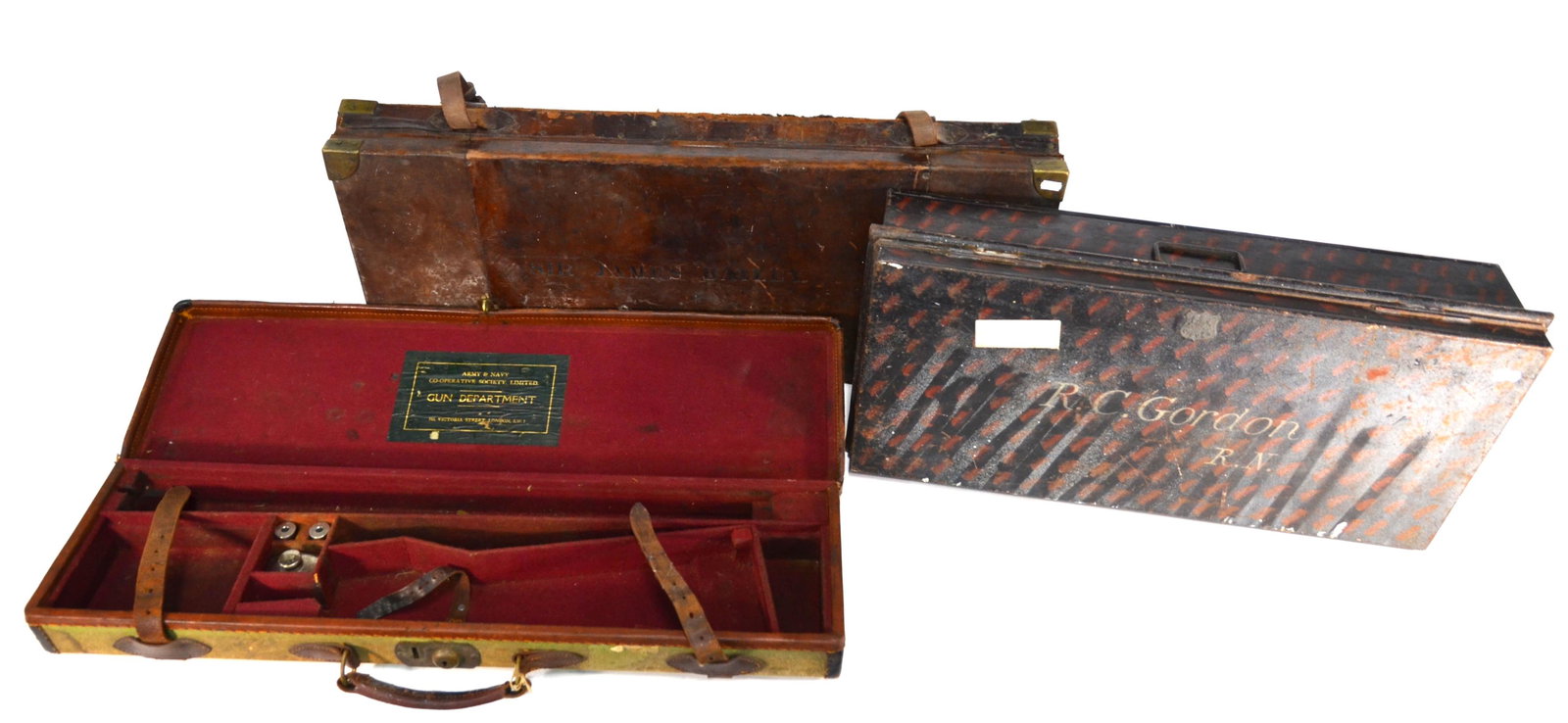 An antique brass bound leather gun case for E M Reilly: An antique brass bound leather gun case for E M Reilly & Co. to/with a leather bound canvas gun case for A&N Leather and a japanned tin trunk stencilled 'R C Gordon R.N. (3)