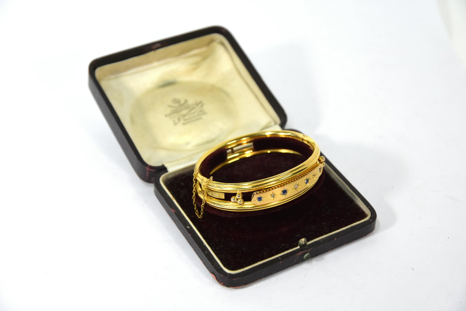 A Victorian sapphire and diamond yellow gold bangle: A Victorian sapphire and diamond yellow gold bangle, with wirework surround, hinged opening and with safety chain, 11.4g all in, within fitted box by E H Durran & Son of Banbury