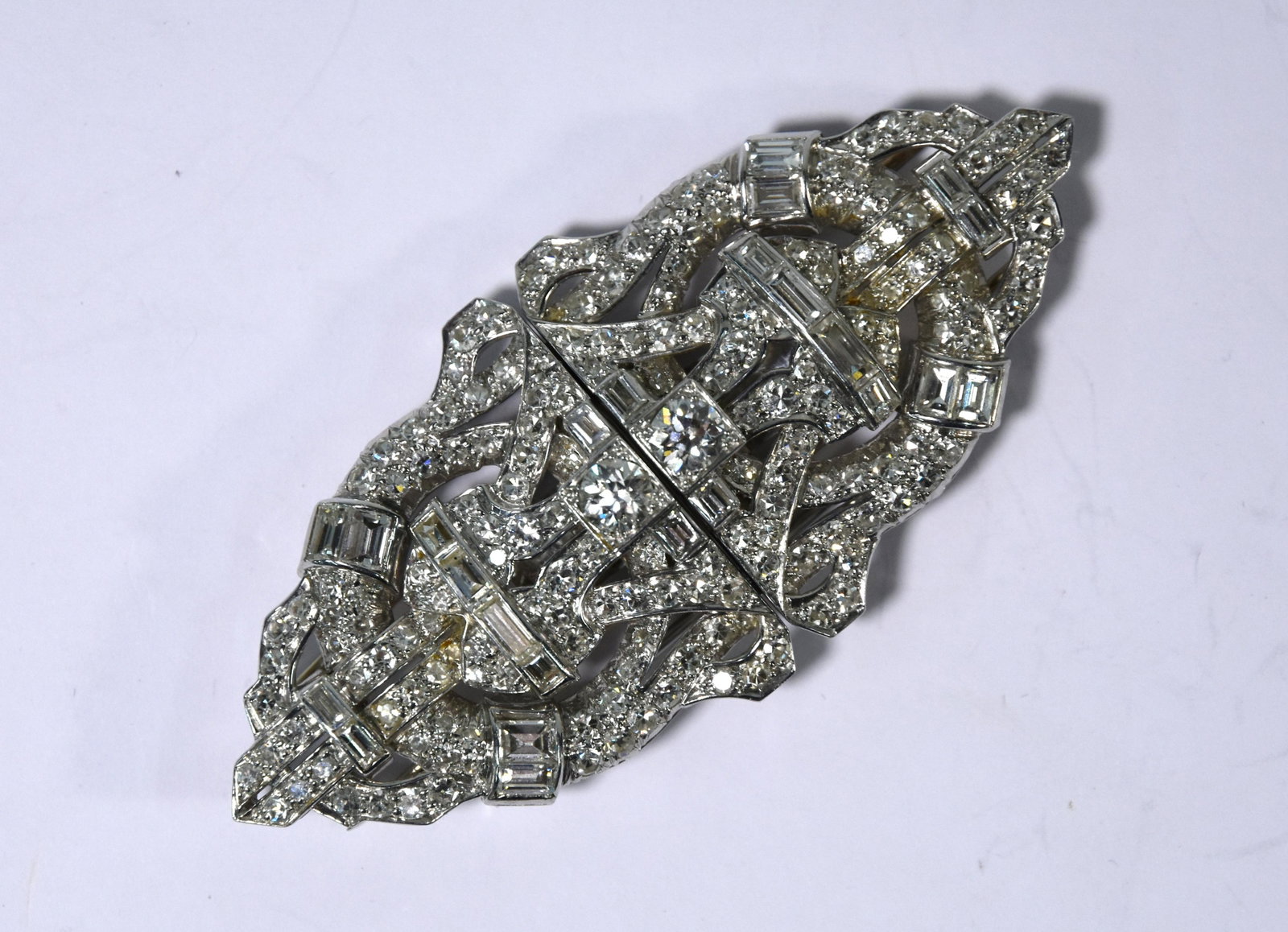An Art Deco diamond double clip brooch: An Art Deco diamond double clip brooch, the symmetrical shaped geometric design profusely set with various cut diamonds, white metal set, 7.4 cm long x 3.5 cm, with detachable brooch conversion, doubl