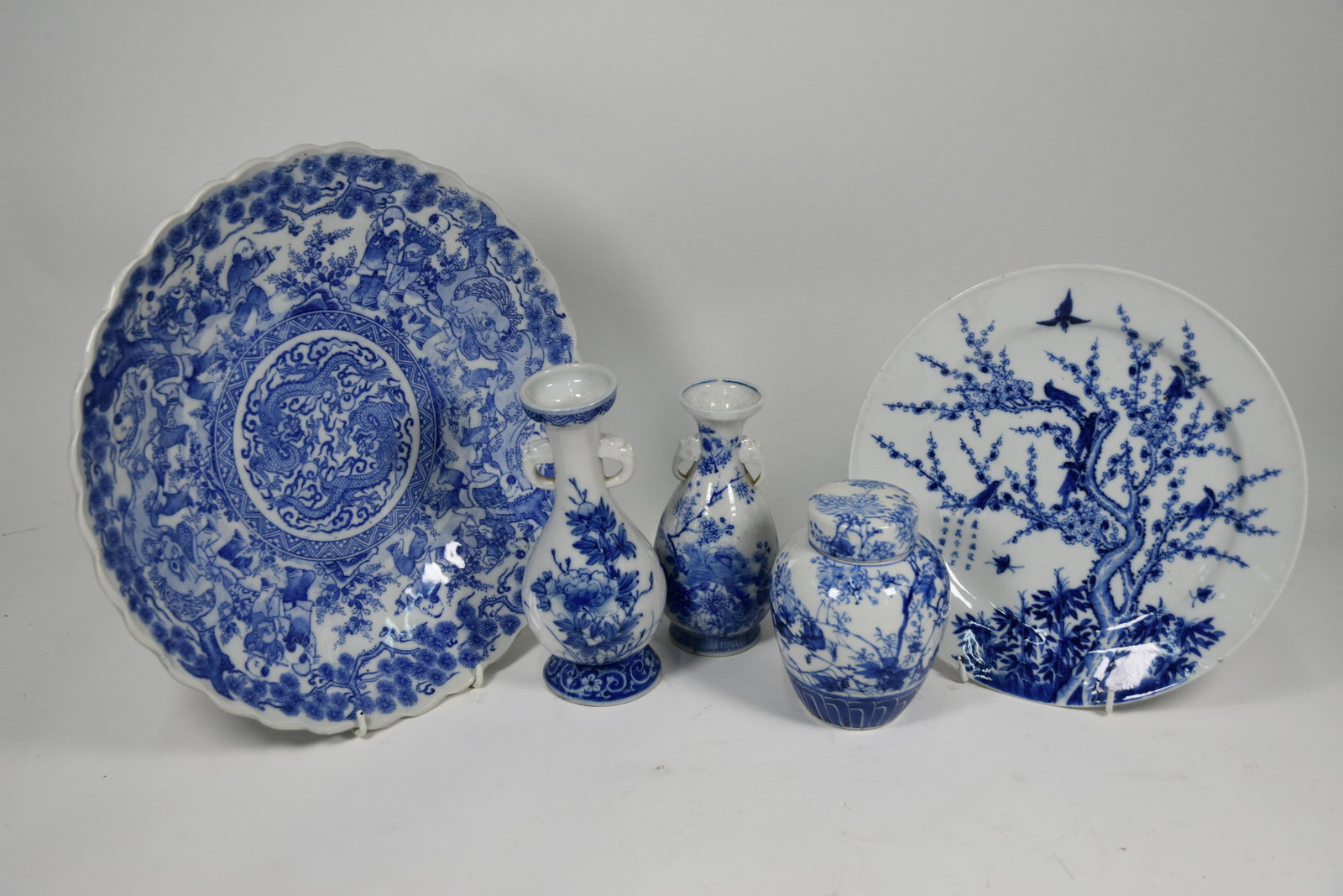 A selection of Japanese Meiji and later, blue and white: A 19th century Japanese porcelain blue and white plate painted with a birds, insects and a blossoming prunus tree next to a calligraphic inscription, all in vibrant tones of underglaze blue, the base 