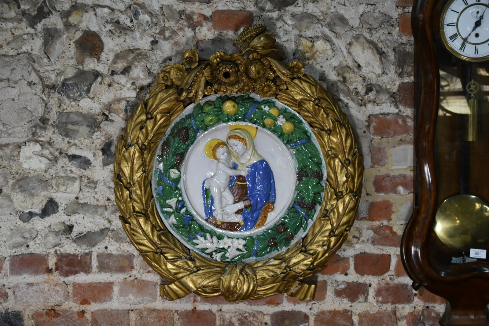 Della Robbia plaque - Madonna and Child: A 19th Century Della Robbia-style pottery plaque, embossed in relief with the Madonna and Child within foliate wreath border with fruit and flowers, 45cm diameter, in well-carved giltwood foliate wrea