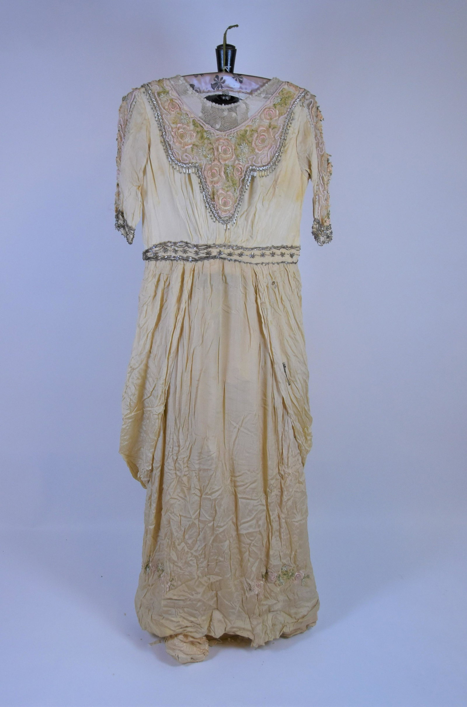 An Edwardian lady's cream evening gown: An Edwardian lady's cream evening gown with short sleeves and beaded and embroidered front panel, beaded waist band and sleeve cuffs, and embroidered edging to bottom of skirt, with ruched sides and u