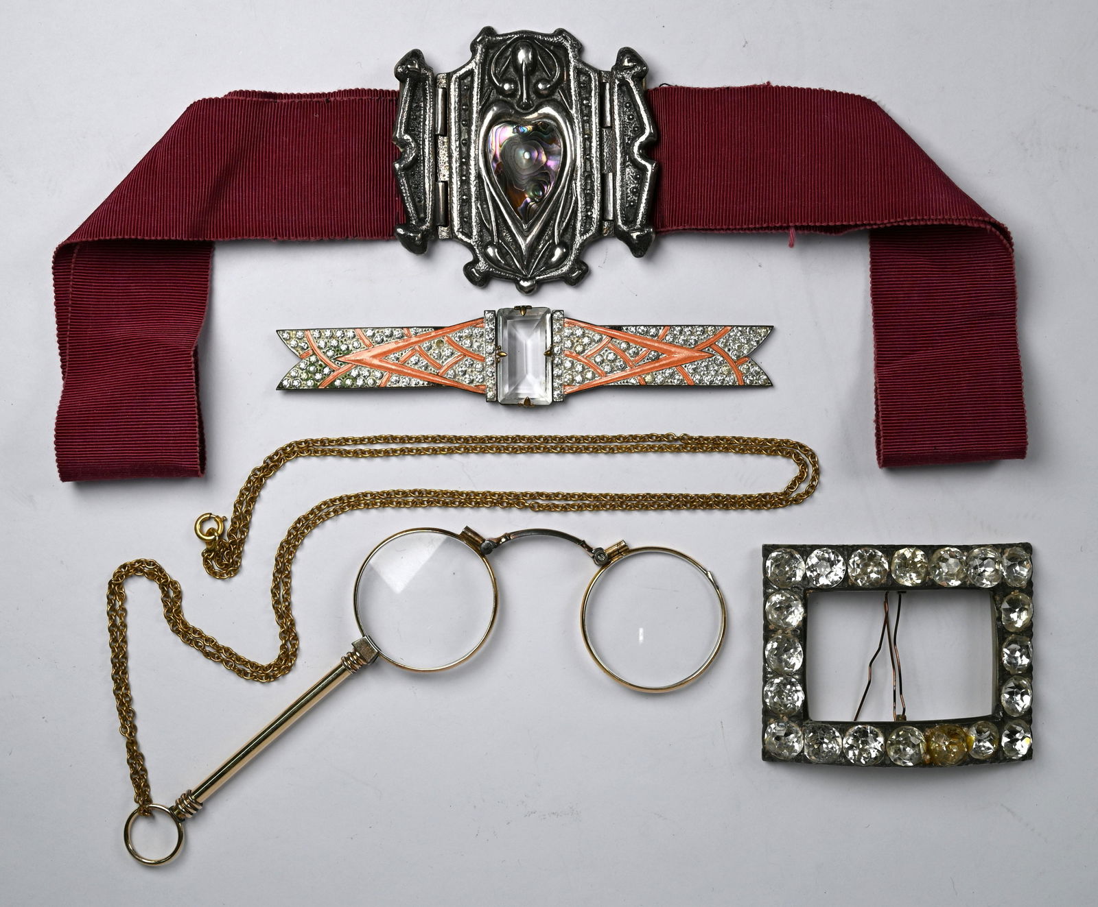 An Art Nouveau style white metal buckle and other items: An Art Nouveau style white metal buckle featuring abalone shell heart to/w large paste set rectangular buckle, French Art Deco paste and enamel dress clip and cased pair of folding lornettes on gilt m