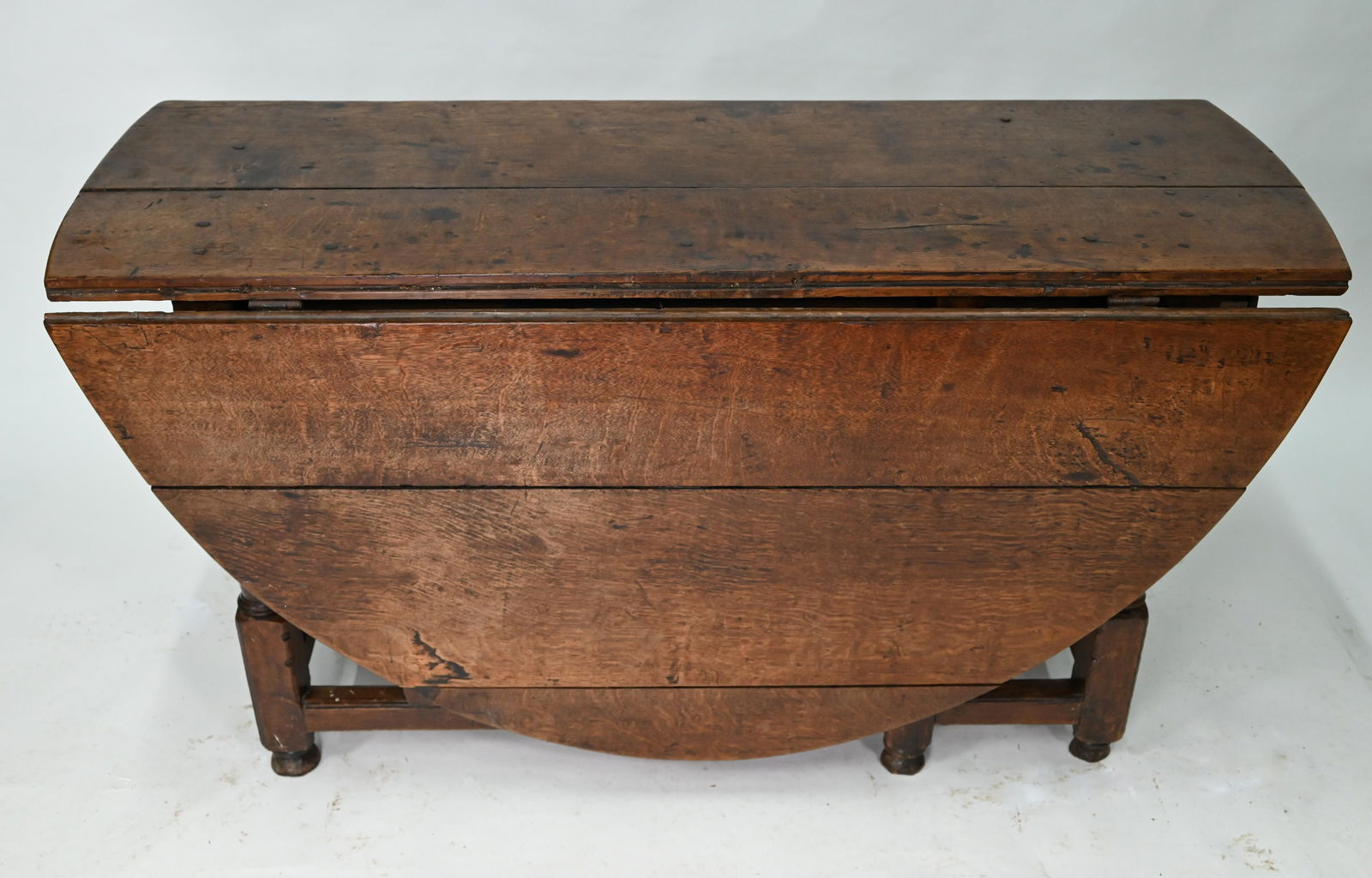 An antique oak gateleg supper table: An antique oak gateleg supper table, the oval top raised on turned and block joint frame, drawer to one end, 136 cm long (53 cm closed) x 168 cm wide x 72 cm high