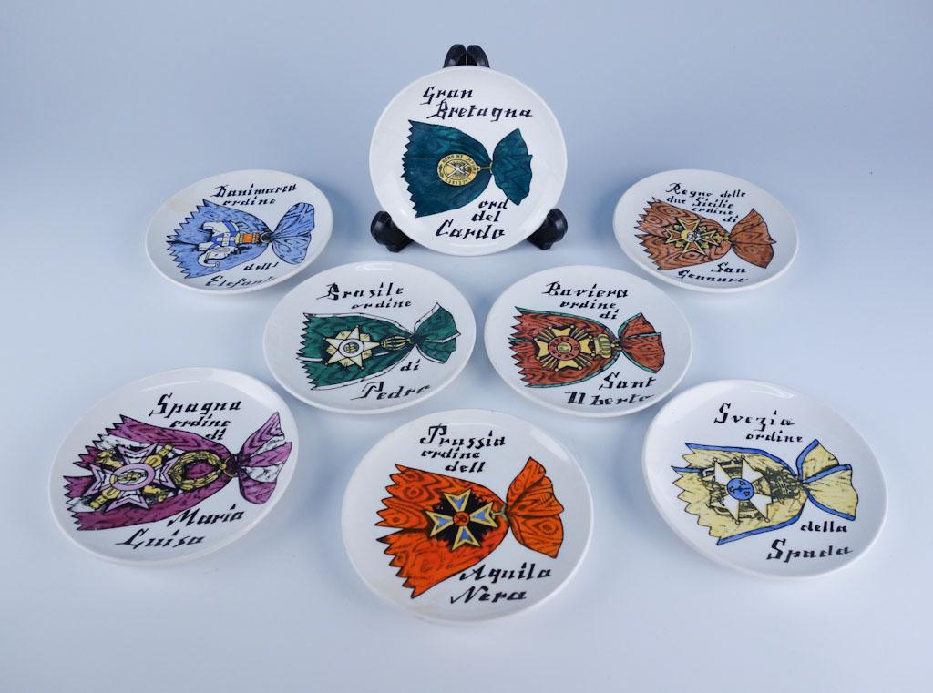 Set 8 Italian Piero Fornasetti Al Merito HP Coasters: Vintage set of eight hand painted art pottery coasters from Piero Fornasetti (1913-1988) of Italy. Decorated in the "Al Merito" pattern with different medals and ribbons on each. 4" diameter