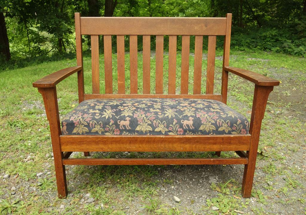 Mission Oak Bench Settee: A mission style wooden bench with cushion featuring flowers and animals. One large stain to top left corner of cushion 47" x 22" x 41 1/2"