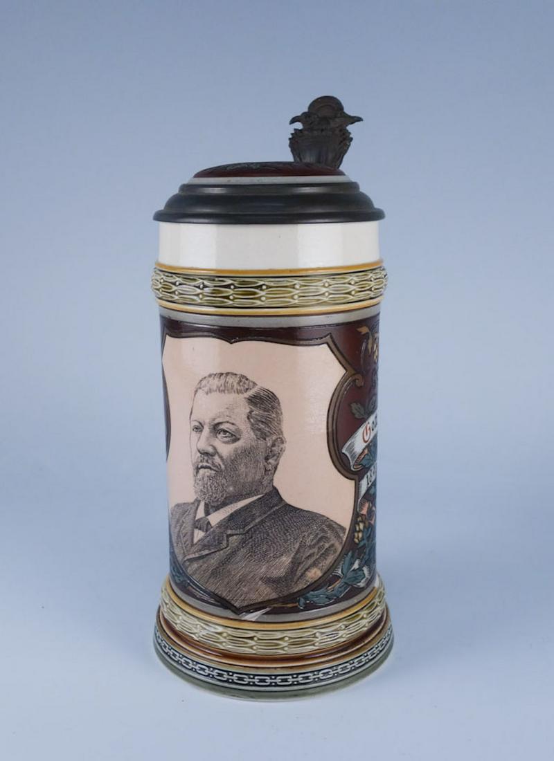 Mettlach Stein #1997 Portrait of George Ehret: This is a Mettlach stein featuring a portrait of a man. The words say "Hopfen u Malz, Gott erhalt's, 1866 - 1892. The lid features a 6-pointed star with the letters "E" and "G" stacked on top of each 