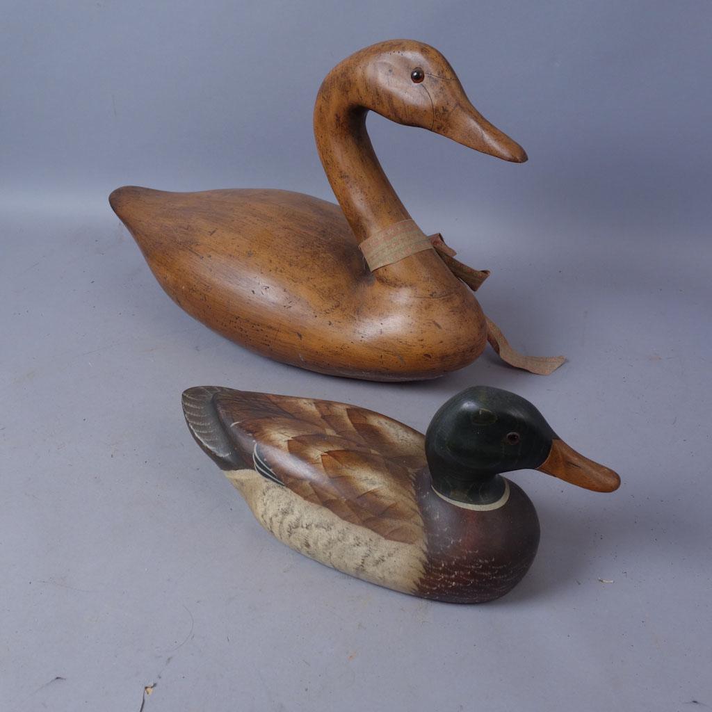 Lot of 2 Wooden Decoy Ducks: Two wooden decoy ducks. Smaller duck is painted, underside marked "Sport'en Art Decoys Big Sky Carvers Bozeman, Montana," handwritten signature"Craig Fellows" Larger decoy has "E-85" carved into under