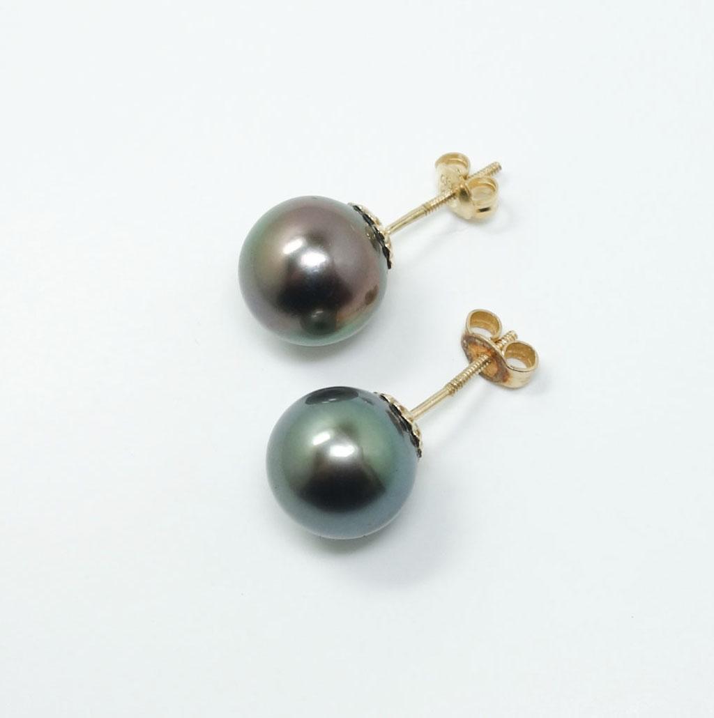 Drue Sanders 14k Gold Tahitian Black Pearl Earrings: This is a charming pair of Drue Sanders Custom Jewelers earrings. Rendered in fine 14k yellow gold, these studs each feature a strikingly large Tahitian black pearl. The earrings are wonderfully displ