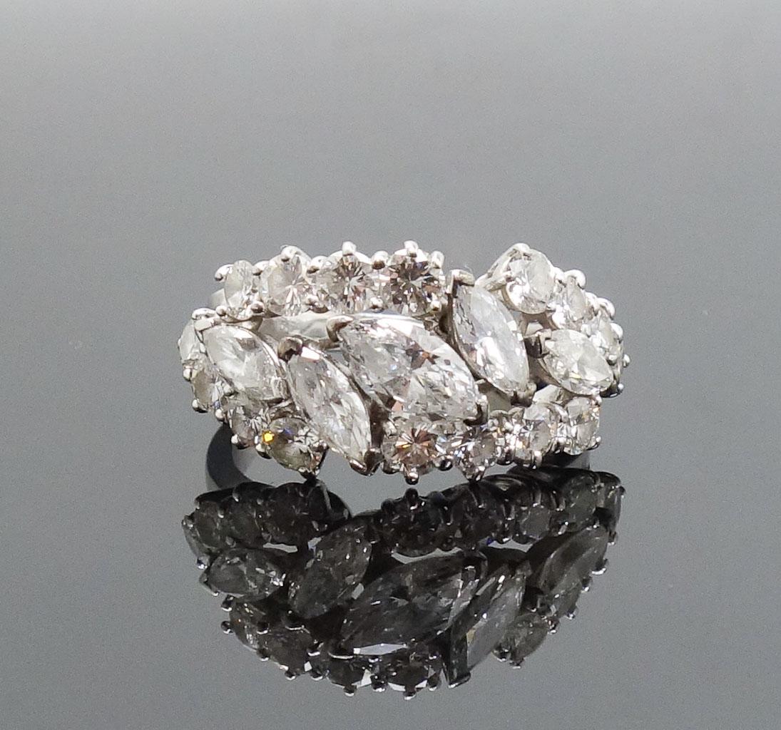 Vintage Platinum Diamond Cluster Band Ring: This is a vintage cluster band ring. Rendered in fine platinum, this ring features 16 small diamonds surrounding 5 larger cut diamonds. US Size 6 1/4. Total weight 9.0g.