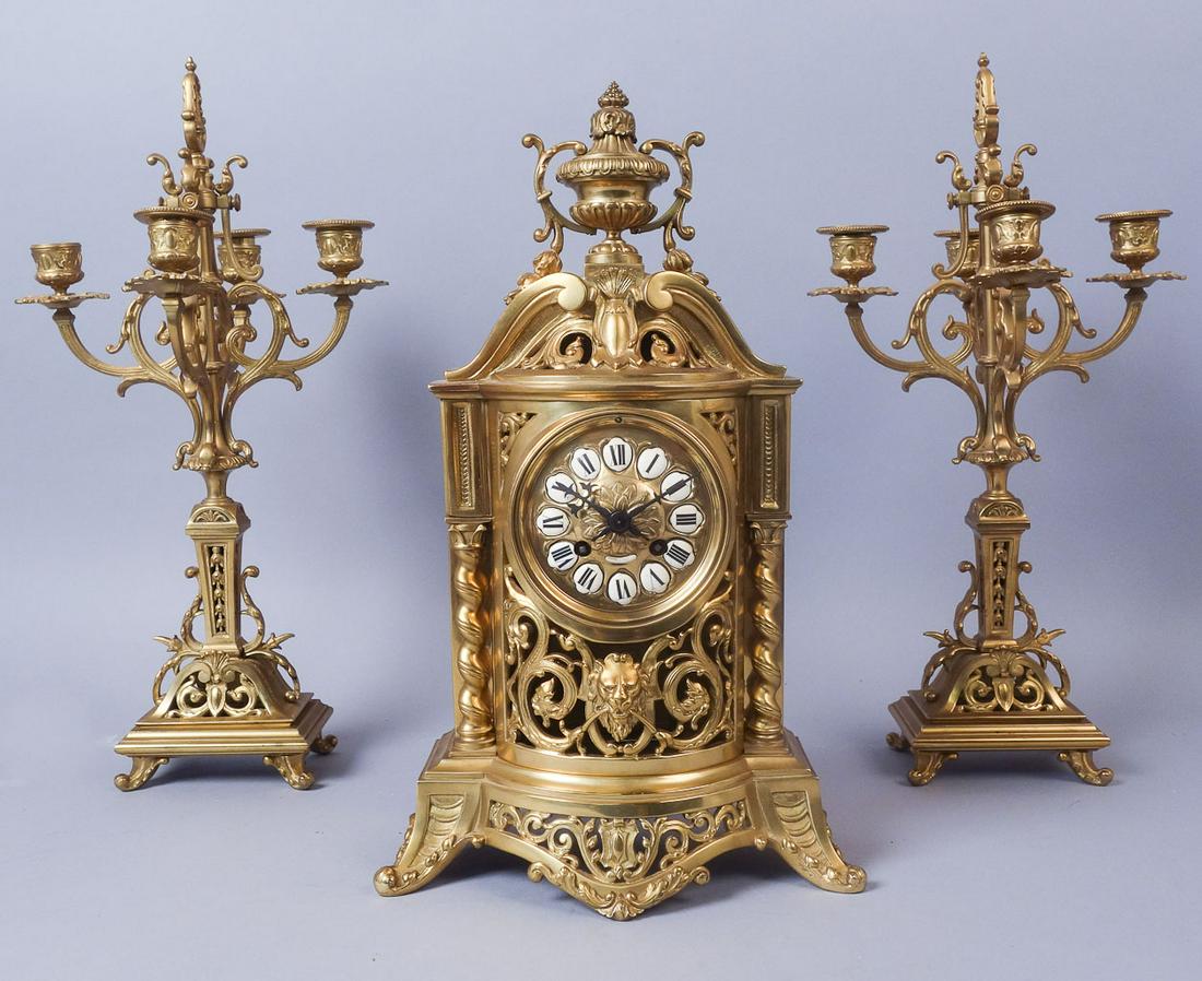 Antique 3 Piece French Bronze Dore Clock Garniture Set: French bronze Dore clock garniture set. The clock has stickers from two stores hand-marked 8/96 and 6/99 respectively. The candlesticks are unmarked. Clock: 17"x 10 1/2"x5 1/2" Candlesticks: 18 1/2"x9
