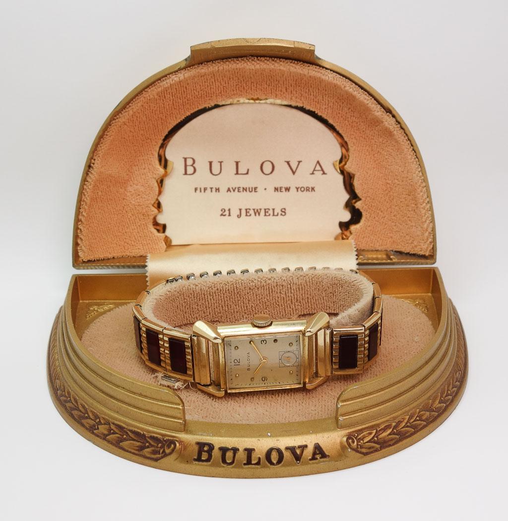 1950s MCM Bulova 14k 21J Mens Wristwatch: Watch accompanied with the original case. Initials FJH inscribed on back of case. Watch weighs 42g. Including box, it weighs 134g. The watch case measures 28.1mm x 21.1mm. The case including the crown