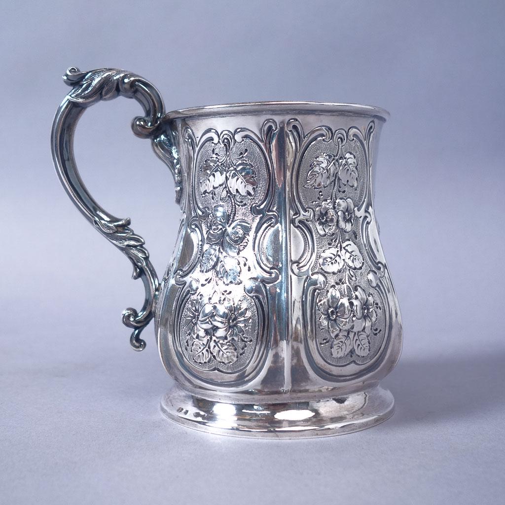 Victorian 1854 Birmingham Sterling Silver Repousse Mug: Beautiful Victorian sterling silver mug crafted in Birmingham, England in 1854. The mug features ornate floral repousse designs. "L.Amty No[illeg]" scratched onto bottom. 6.58ozt. 4 1/2" x 4 3/4" x 3 