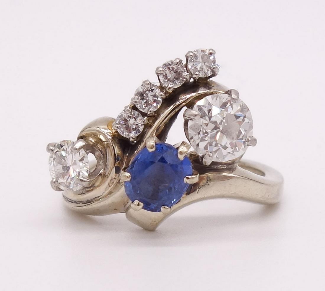 14K White Gold Violetish-Blue Sapphire Diamond Ring: This size 5.75 ring in 14K white gold features an oval faceted violetish-blue sapphire and six full cut round diamonds of various sizes prong set in a swirled cluster. The ring is a size 5.75. It weig