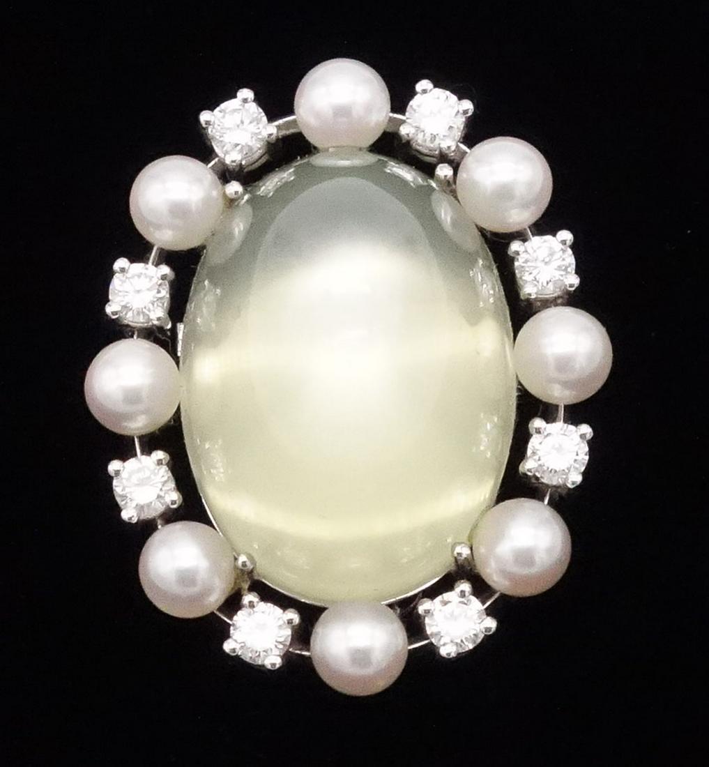 18K White Gold Diamond Moonstone Pearl Brooch: This 18K white gold brooch features a yellowish-green oval moonstone cabochon with a halo of round diamonds and round white pearls. The moonstone that measures approximately 21.2 x 15.4 x 14.4mm at ap