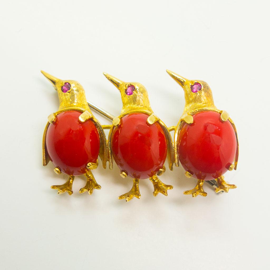 Italian 18K Gold Ruby Coral Triple Penguin Brooch: This Italian vintage brooch pin is rendered in 18K yellow gold. This pin features three penguins adorned with coral cabochons on their stomachs and ruby eyes. It measures 1 3/8 x 7/8", the coral caboc