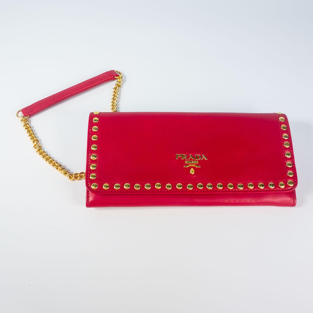 Designer Prada Red Calfskin Leather Wallet Bag: This red calfskin leather Prada wallet bag features gold colored hardware and studs with a detachable chain strap. This bag measures 7.5 x 4 x 1" and the chain is 45.5".