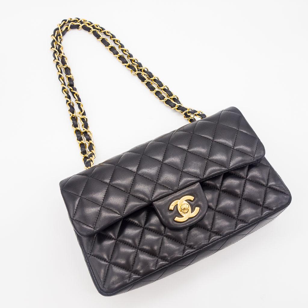 Chanel Small Classic Handbag in Black Lambskin: This Small Classic Handbag by Chanel features a black lambskin diamond quilt with a double fold top and gold-one hardware. This bag has its original paperwork. It measures 9" x 5.7" x 2.3" and the aut