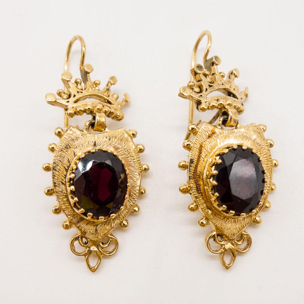 14K Gold Renaissance Revival Garnet Dangle Earrings: This pair of vintage earrings is rendered in 14K gold. The Renaissance Revival style earrings feature large faceted garnets topped with crown finials. Each is 1 5/8" long. The garnets are each 10 x 8 