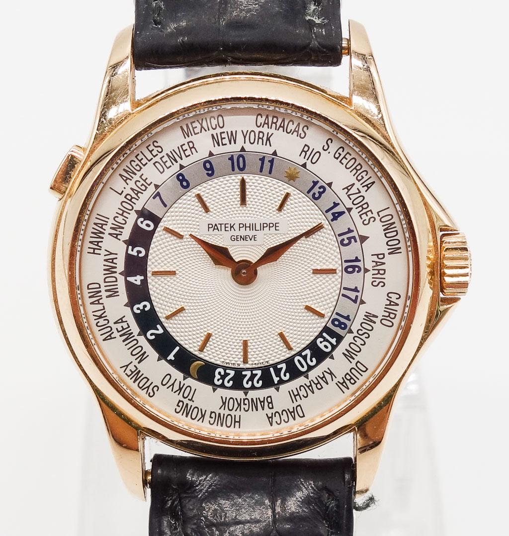 Patek Philippe 18K Rose Gold World Time Wristwatch: This exquisite 37mm Patek Philippe World Time wristwatch is made in 18K rose gold with a guilloche opalin dial and a black crocodile strap with a deployment buckle. This timepiece is 37mm, the referen