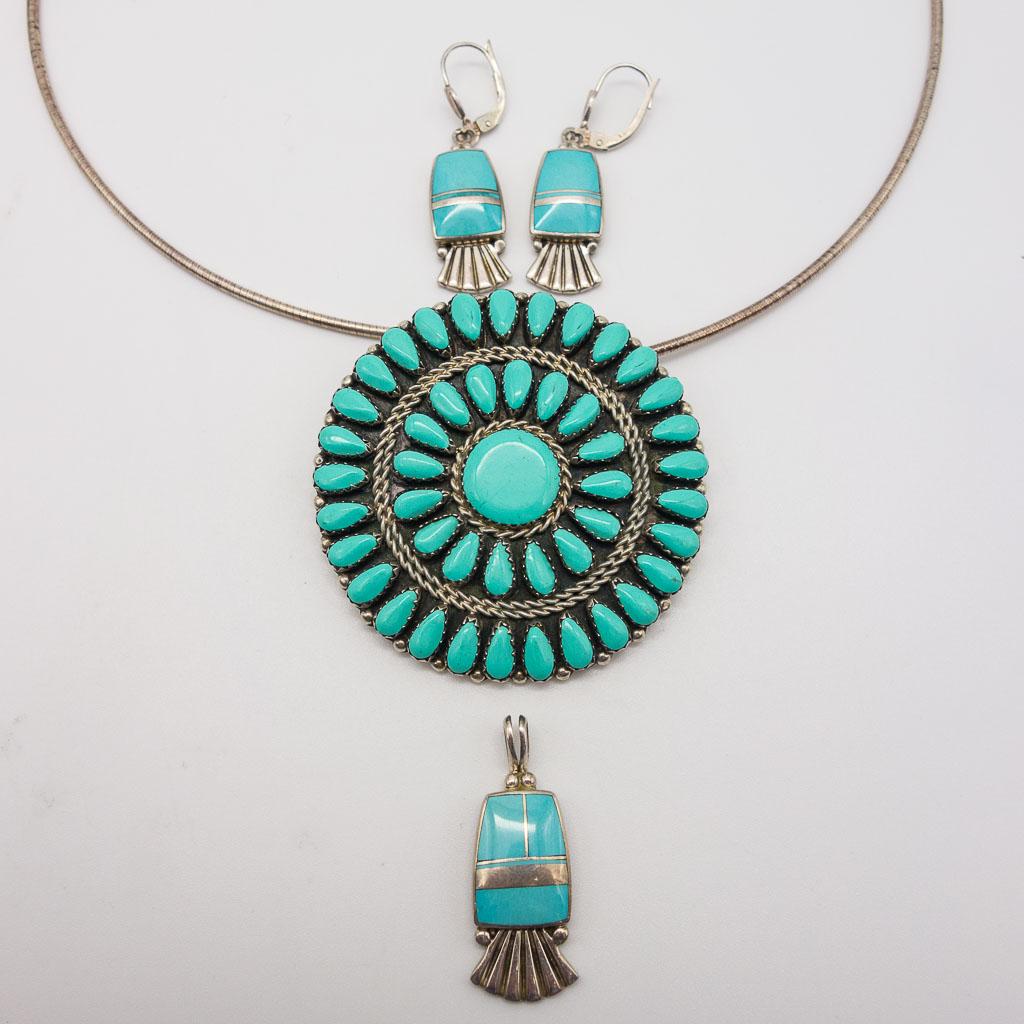 Sterling Silver Turquoise Petit Point Pendant Earrings: This is a lot of Native American sterling silver turquoise jewelry. Rendered in sterling silver, this lot includes a Zuni petit point pendant (signed MB), and a turquoise inlay earrings and pendant su