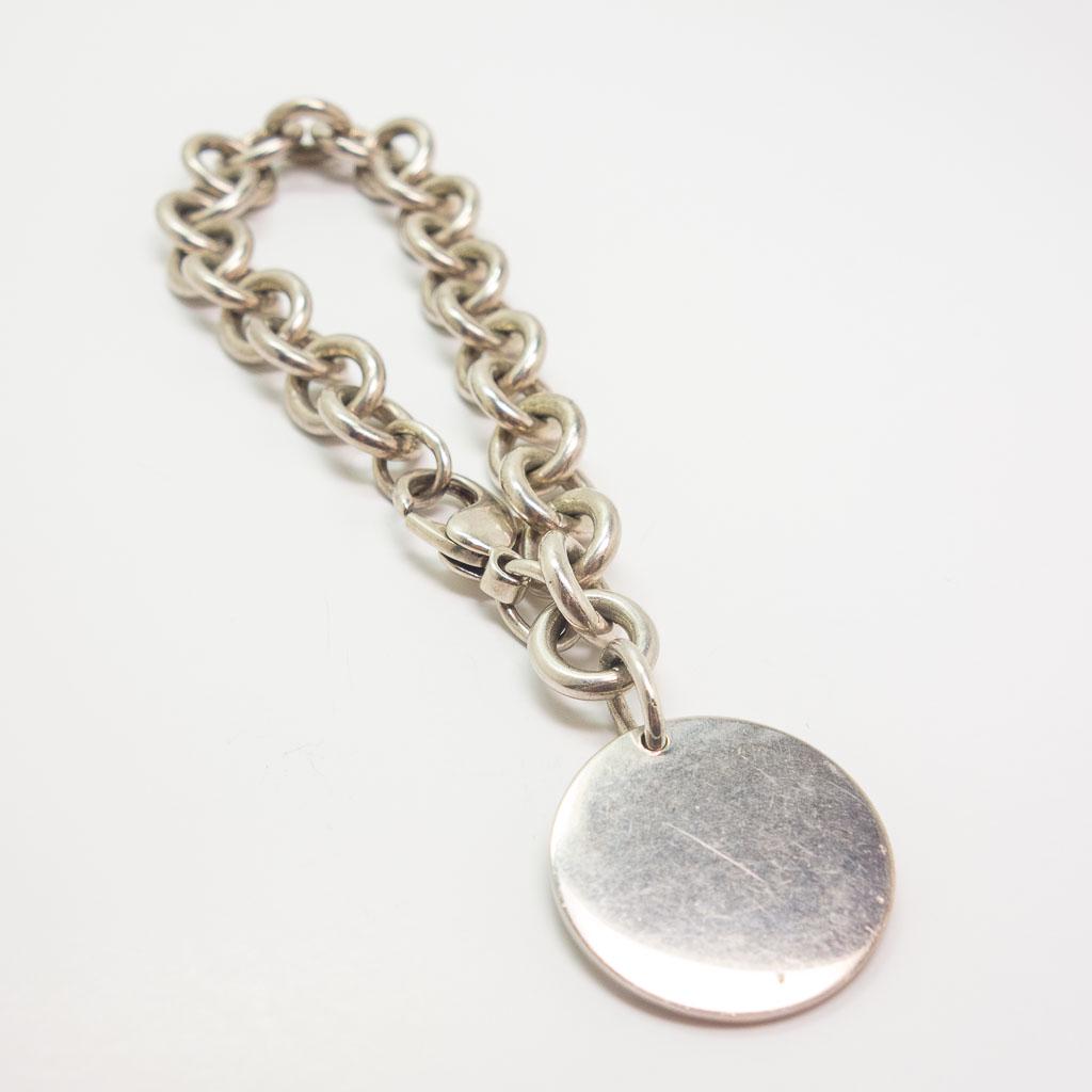 Tiffany Sterling Link Charm Bracelet w Disc Charm: This is an elegant vintage Swiss Universal Geneve ladies wristwatch retailed at Tiffany & Co. Rendered in fine 14K yellow gold, this slim watch case frames a gold tone dial with Roman Numeral indices.