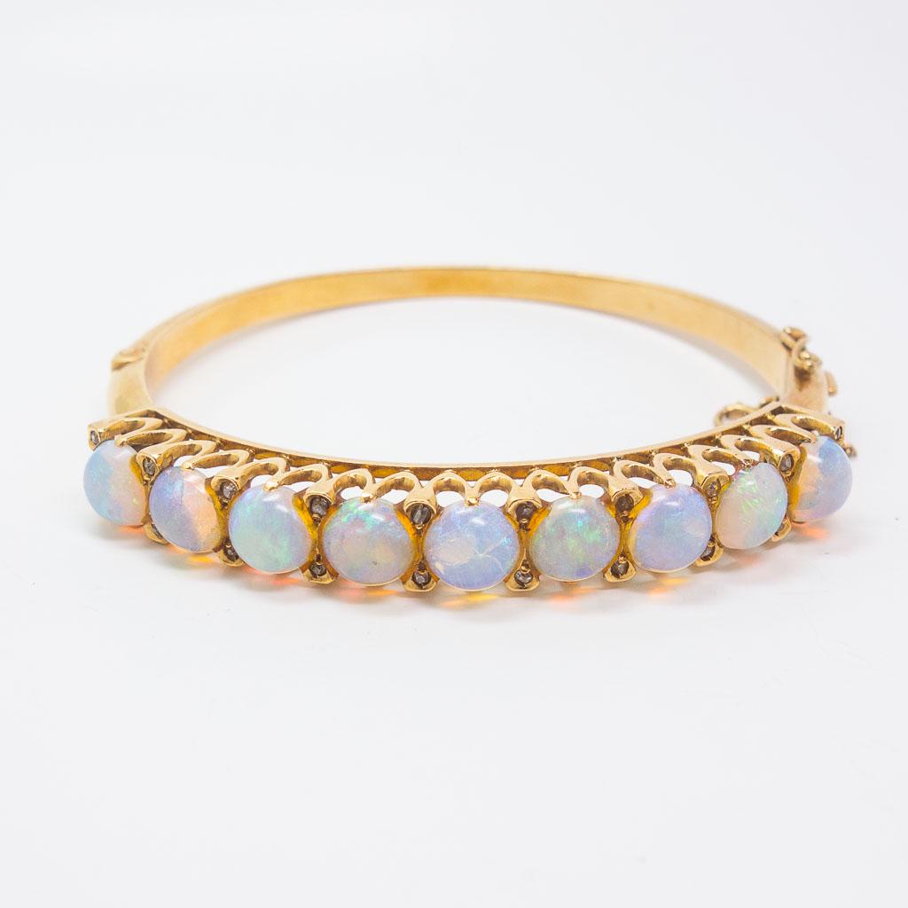 14K Yellow Gold Australian Opal Diamond Hinged Bracelet: This 14K yellow gold hinged bangle features 9 white Australian opals and round diamonds. The interior circumference is 6.5". The opal cabochons measure 7mm each and diamonds that are approximately 0.1