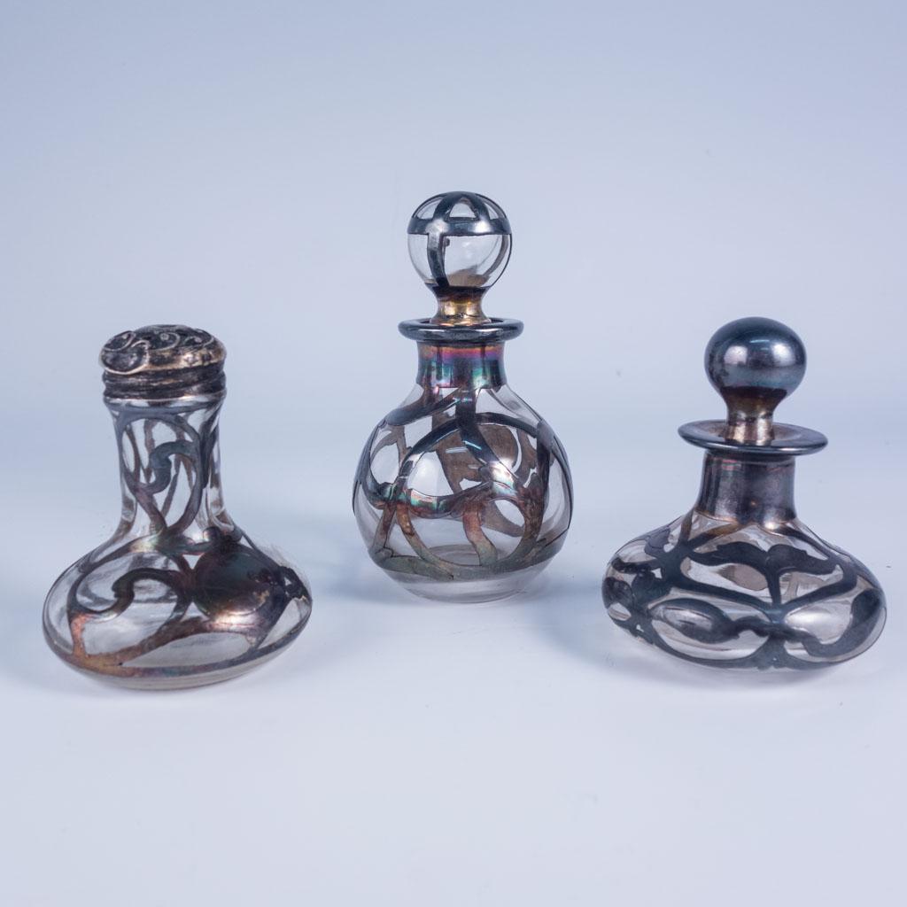 Antique Art Nouveau Glass Bottles w Sterling Overlay: Three antique Art Nouveau glass bottles with sterling silver overlay. Two are perfume bottles and one is a salt or pepper shaker. Largest 3 3/4" Tall, Smallest 2 3/4" Tall