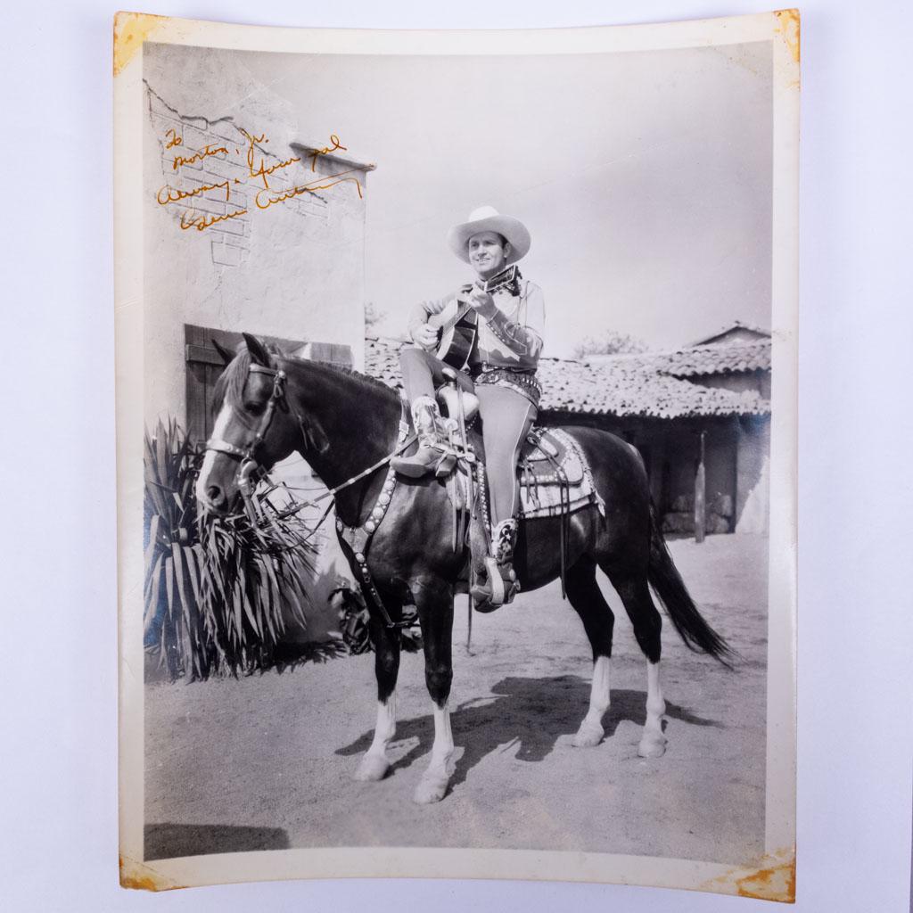 Autograph Signed Photograph of Gene Autry on Horse: An autographed photograph of American singer Gene Autry on a horse with a guitar. We guarantee the authenticity of all autographs for the lifetime of the buyer. 10 x 8"